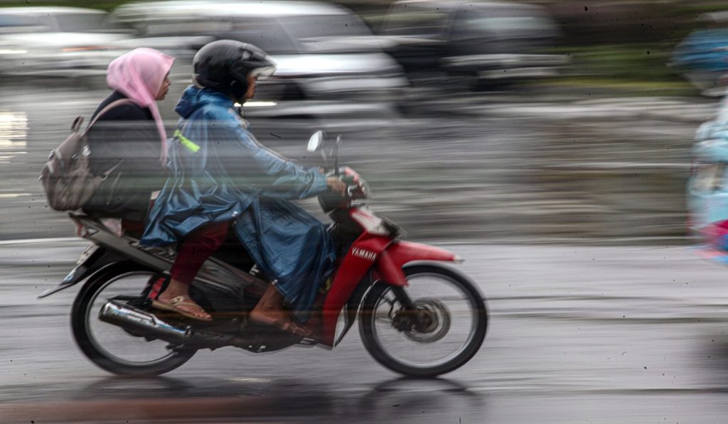 Pengendara sepeda motor memakai mantel saat hujan di Jalan Raya Bogor, Cibinong, Kabupaten Bogor, Jawa Barat, Rabu (4/12/2024).