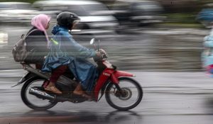 Pengendara sepeda motor memakai mantel saat hujan di Jalan Raya Bogor, Cibinong, Kabupaten Bogor, Jawa Barat, Rabu (4/12/2024).