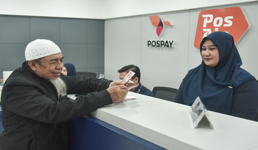 Seorang pensiunan (kiri) menghitung uang pembayaran pensiun di Kantor Pos Lapangan Banteng, Jakarta Pusat, Selasa (1/7/2025).