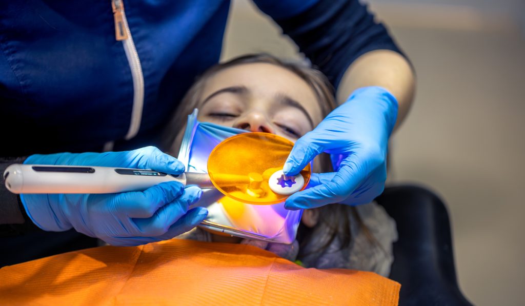 Dental fillings. Dental fillings with ultraviolet light. Female dentist treating a girl's tooth.