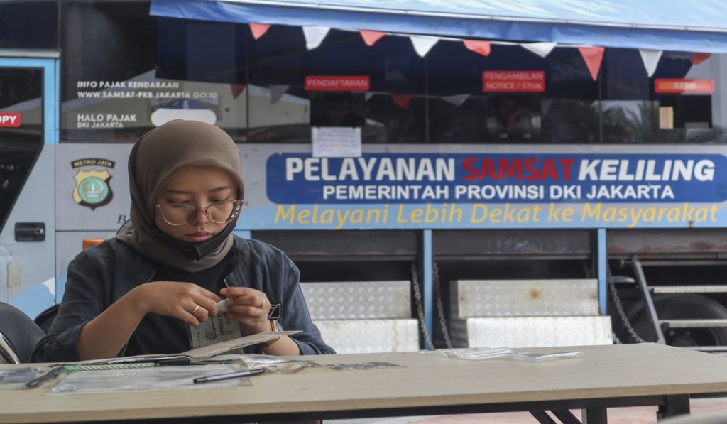Seorang warga memeriksa kelengkapan dokumen kendaraan di gerai pelayanan samsat keliling Lapangan Banteng, Jakarta, Selasa (11/11/2025).