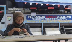 Seorang warga memeriksa kelengkapan dokumen kendaraan di gerai pelayanan samsat keliling Lapangan Banteng, Jakarta, Selasa (11/11/2025).