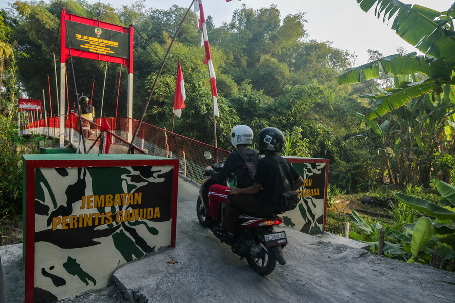 Warga melintasi jembatan gantung garuda menggunakan sepeda motor di Dusun Santan, Kalurahan Guwosari, Kapanewon Pajangan, Kabupaten Bantul, DI Yogyakarta,
